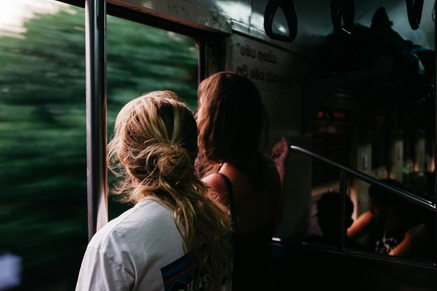 two women traveling by train looking through a window